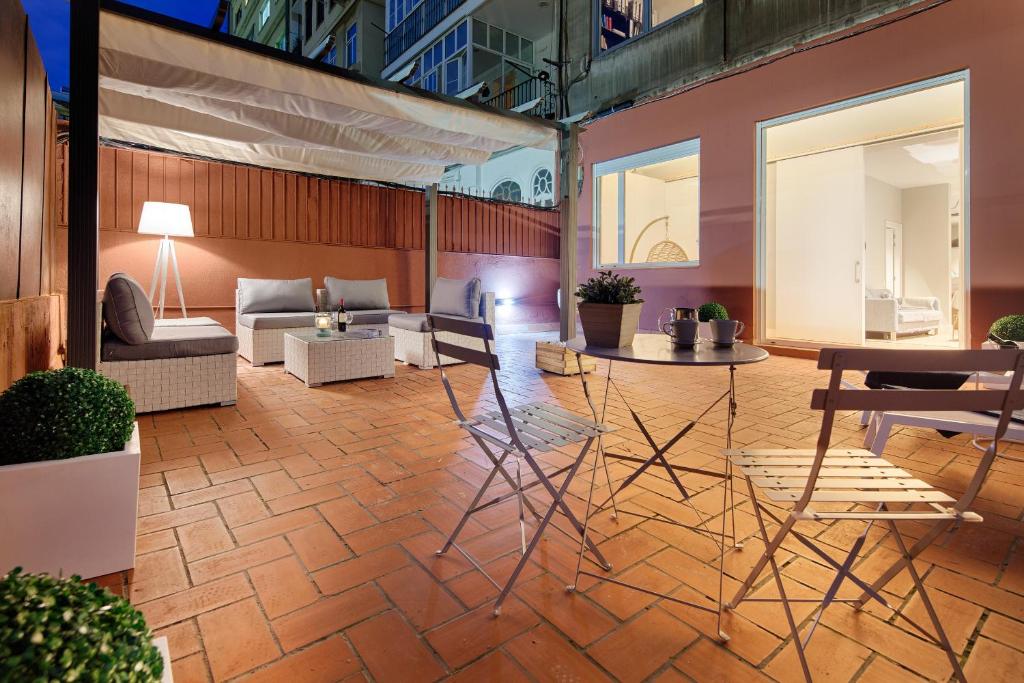un patio avec des chaises et des tables dans un bâtiment dans l'établissement Habitat Apartments Barcelona Plaza, à Barcelone