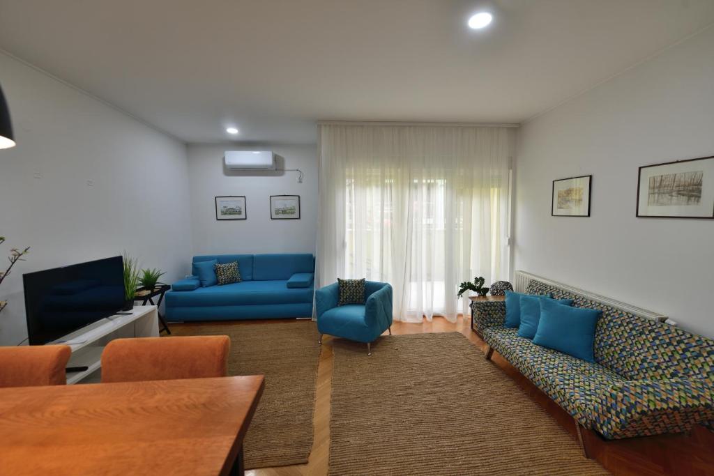uma sala de estar com sofás azuis e uma televisão em Apartman Miran em Osijek