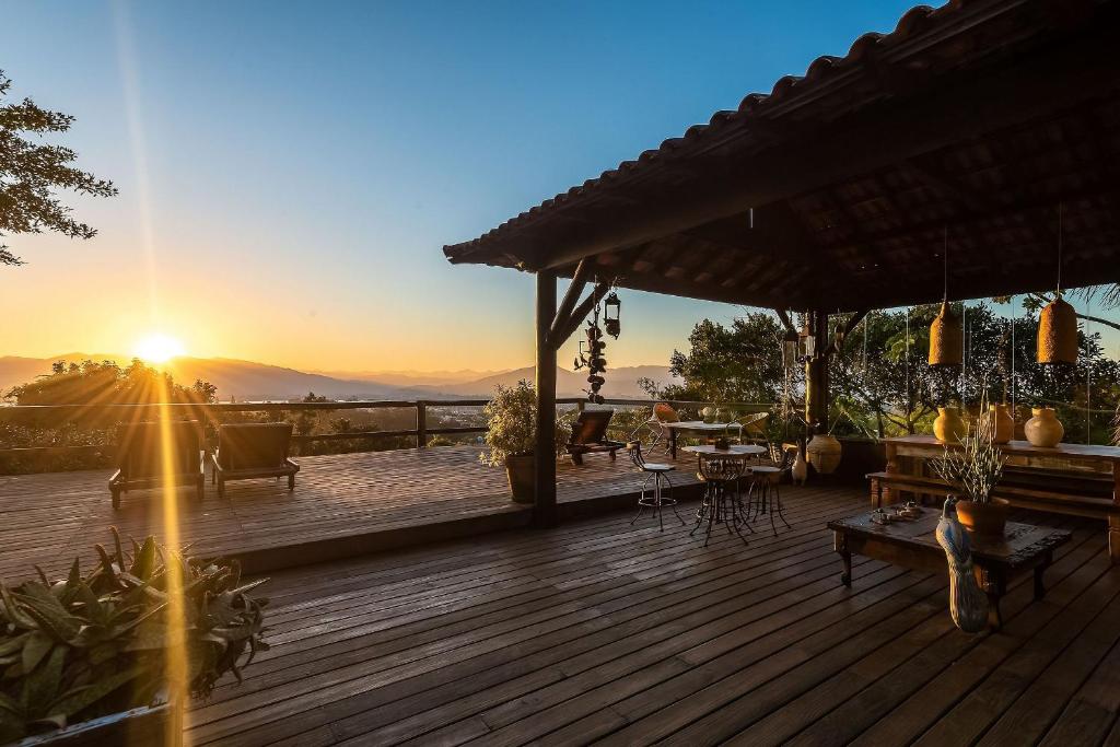 una terraza de madera con una puesta de sol en el fondo en Pousada Casa do Ceo, en Praia do Rosa
