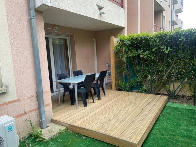 a wooden deck with a table and chairs on a house at Superbe appartement dans résidence avec piscine in Toulouse