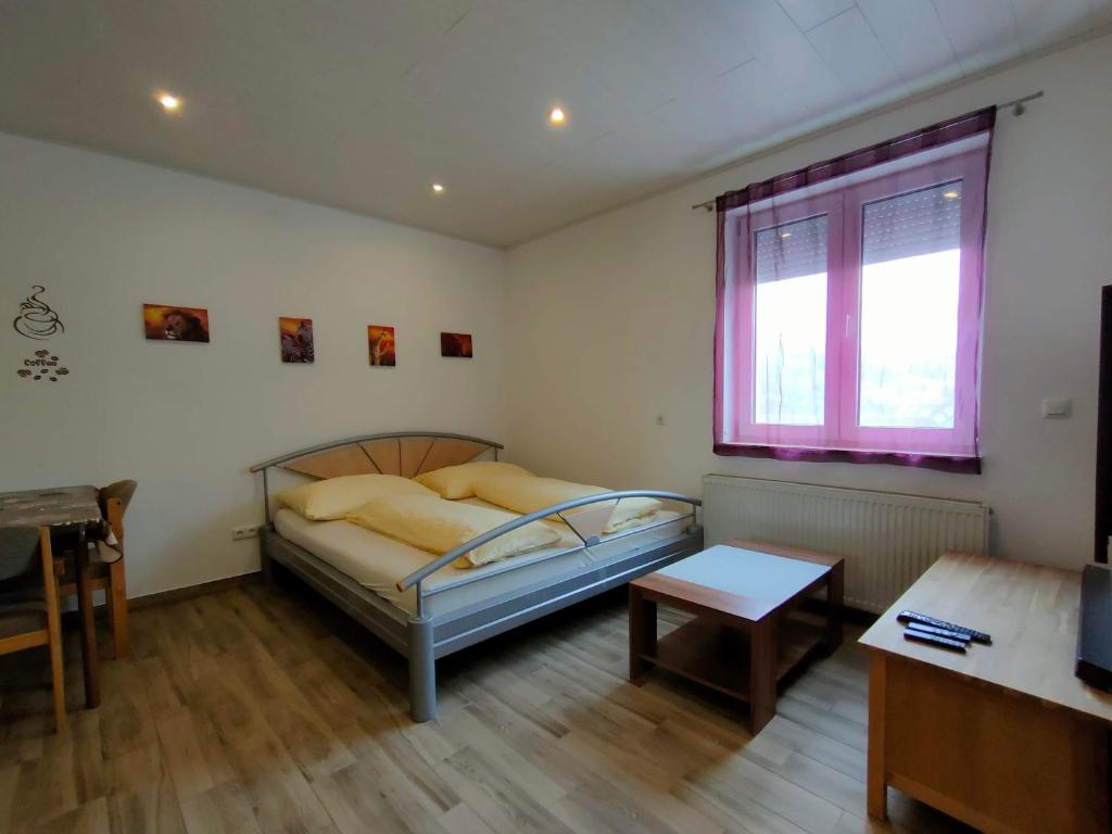 een slaapkamer met een bed, een tafel en een raam bij Monteurzimmer in Kaufing