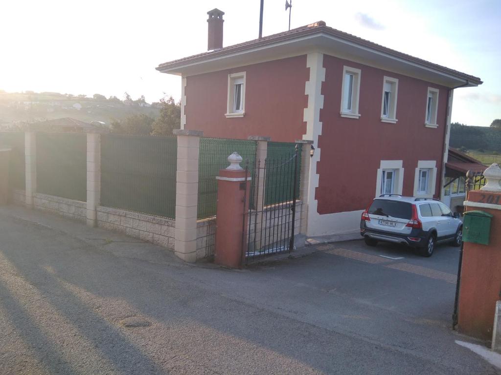 uma casa vermelha com uma cerca e um carro estacionado em frente em Casa Bayona em Monte