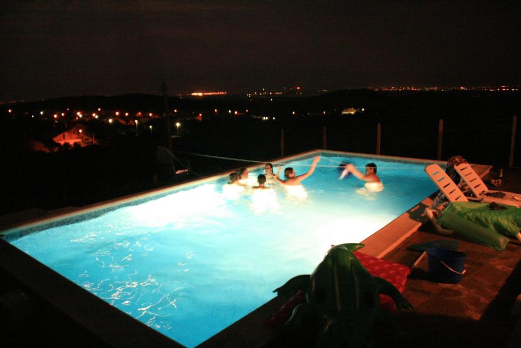 a group of people swimming in a swimming pool at night at Villa Sanaan in Bryastovets