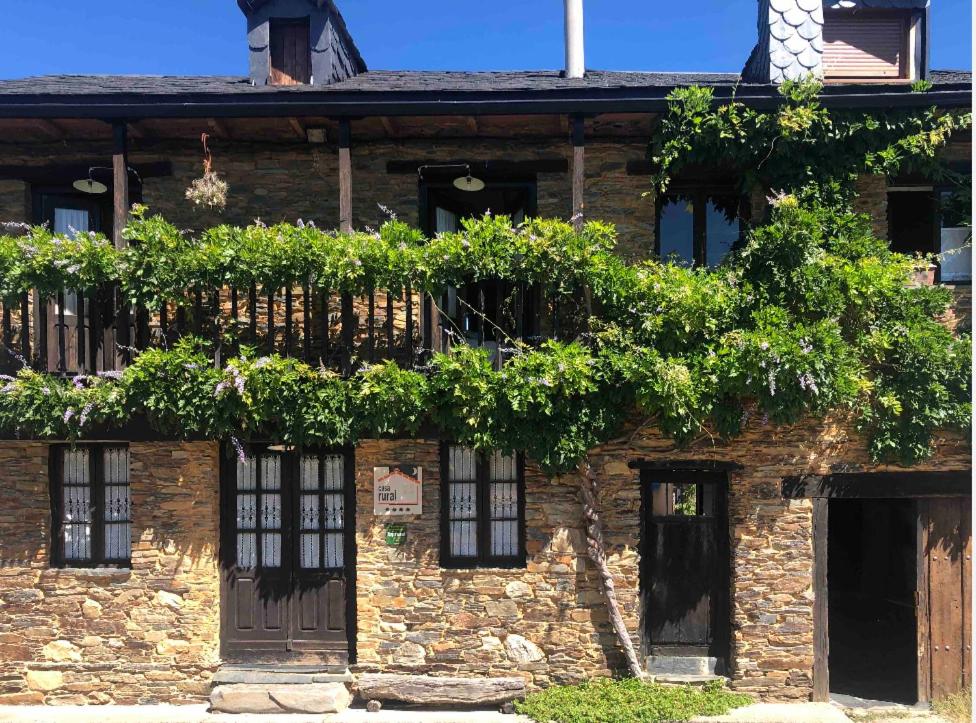 un edificio de ladrillo con ventanas y plantas. en Casa rural **** El Barreiro. Ideal para familias. en Sorbeda
