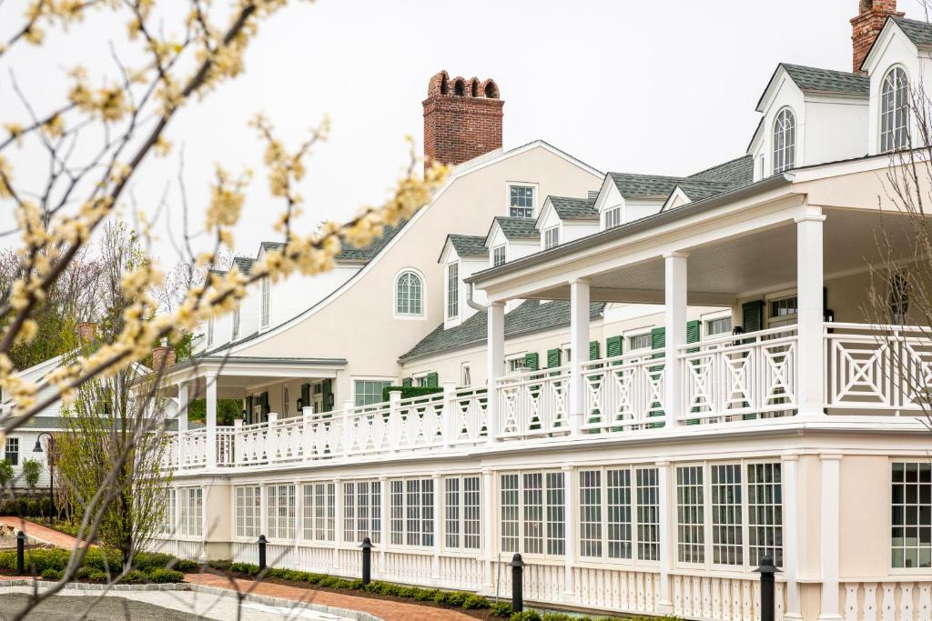 a large white house with a white balcony at Canoe Place Inn & Cottages in Hampton Bays