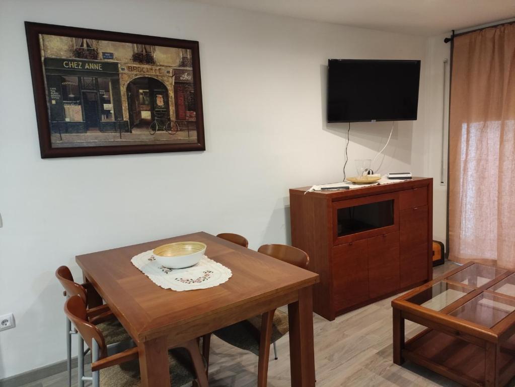 a living room with a wooden table and a television at La LLana Nova in Ribes de Freser