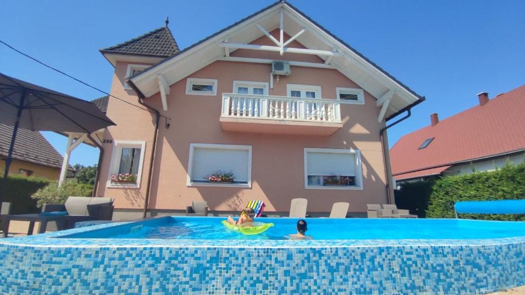 una persona en una piscina frente a una casa en Greta ház en Balatonlelle