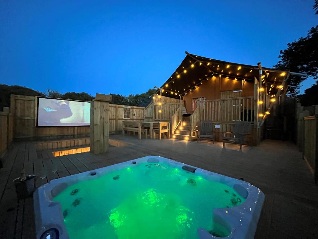 un patio trasero con piscina por la noche con luces en Aladdin Safari Tent en Tenby