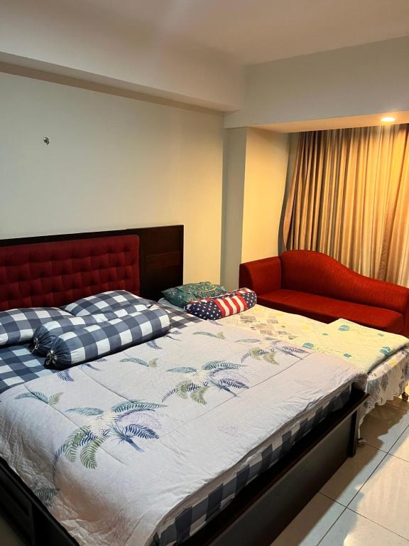 a bedroom with a large bed and a red couch at Sewa Apartemen Jogja MATARAM CITY in Kejayan