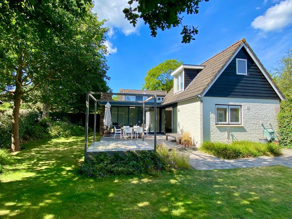 a house with a patio and a lawn at Heerlijk vrijstaand huis aan de duinen in Burgh Haamstede