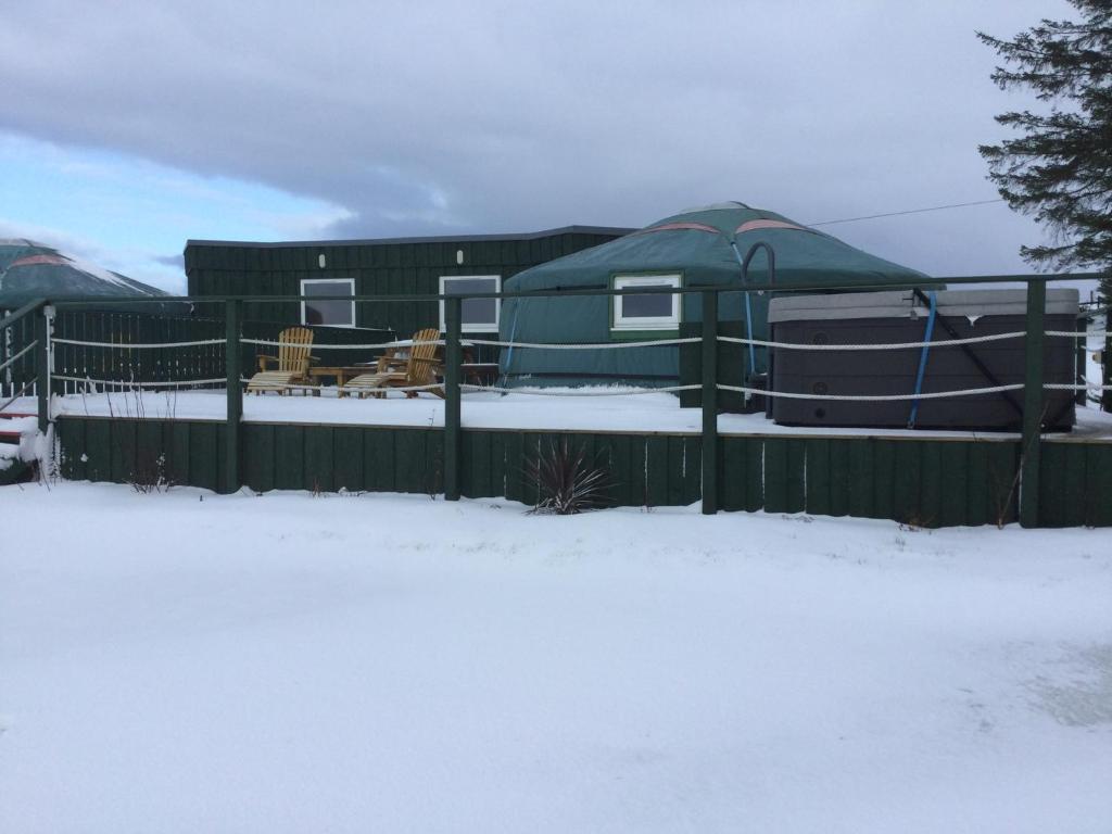 a green fence in the snow with a yurt at Colourful Mongolian Yurt enjoy a new experience in Turriff