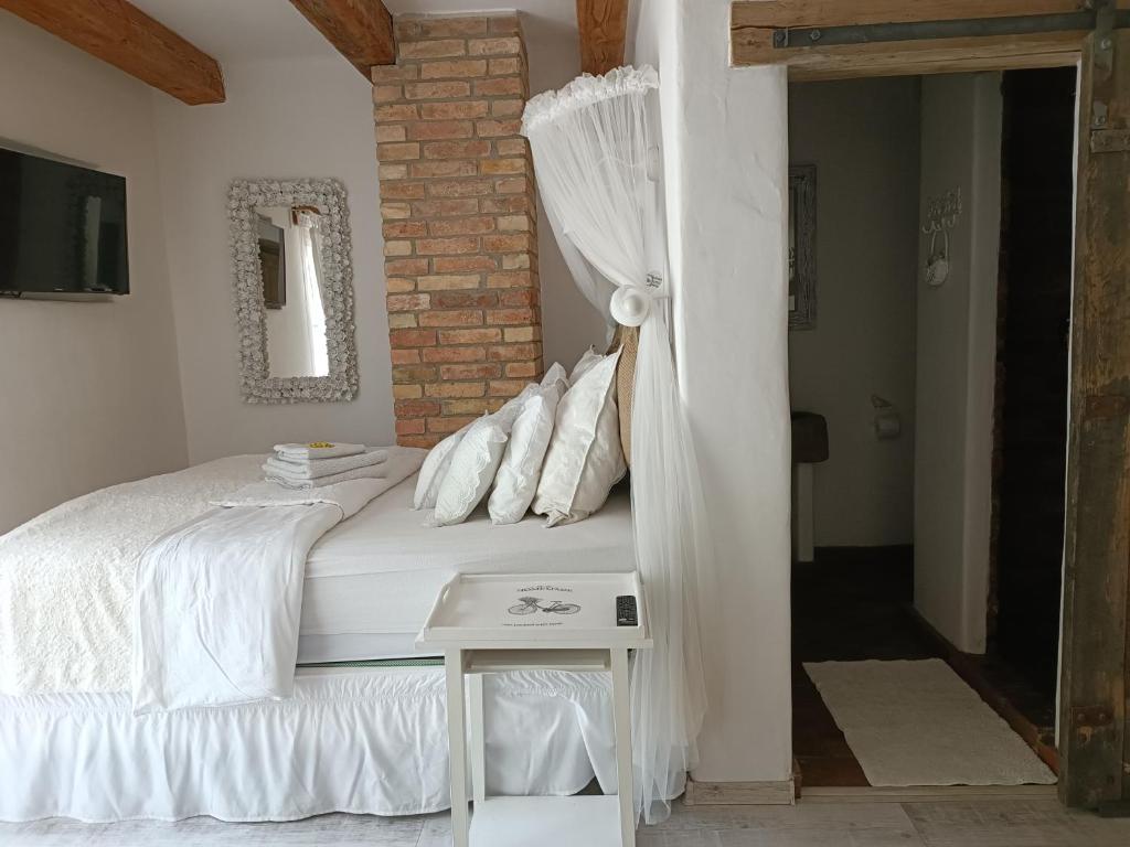 a bedroom with a white bed with a white curtain at Květinový apartmán se soukromou terasou in Pouzdřany