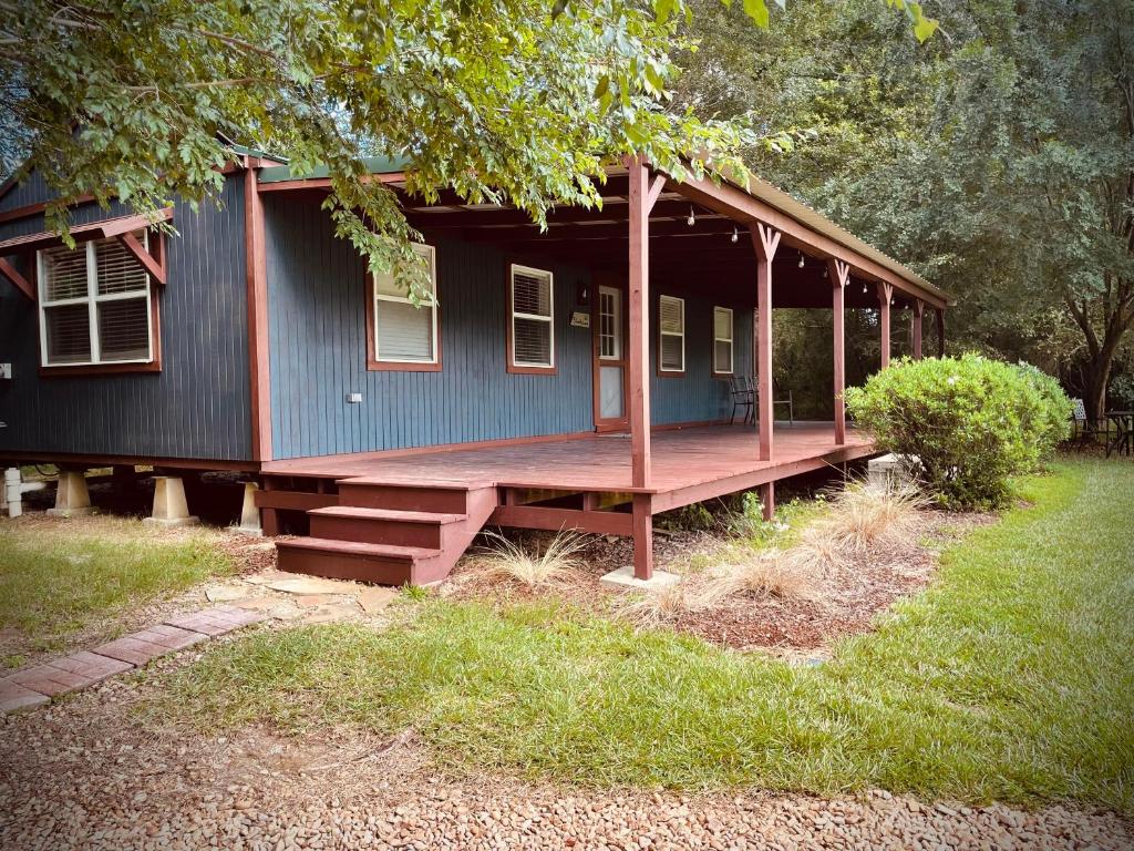 una pequeña casa azul con un porche en un patio en Cabin 3 - Modern Cabin Rentals in Southwest Mississippi at Firefly Lane en Summit