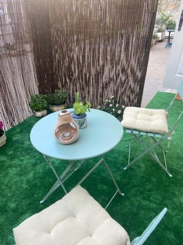 une table et deux chaises sur un sol vert avec une table et des chaises dans l'établissement Beautiful apartment with terrace Centre Nice, à Nice