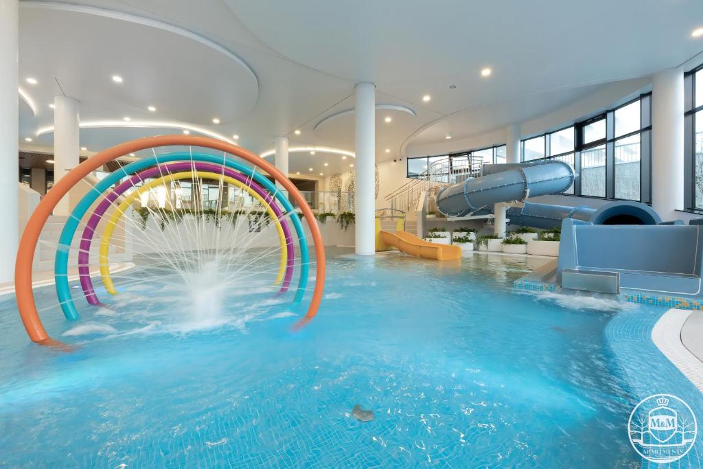a pool with a water slide in a building at Polanki Aqua - Aquapark - Apartments M&M Kołobrzeg in Kołobrzeg