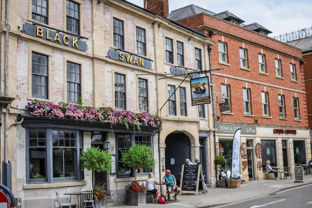 Une scène de rue avec des gens assis à l'extérieur d'un bâtiment dans l'établissement The Black Swan Inn, à Devizes