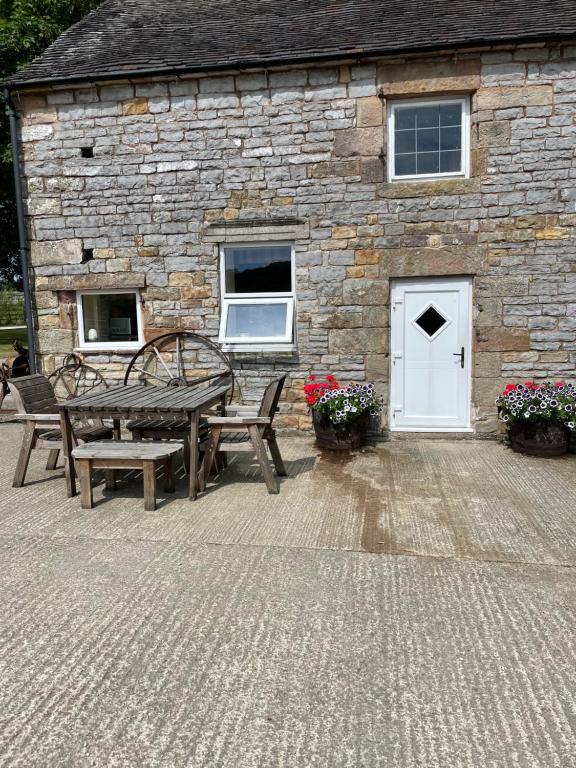 a stone building with a table and benches in front of it at Boujie Barn- Shippon in Waterfall