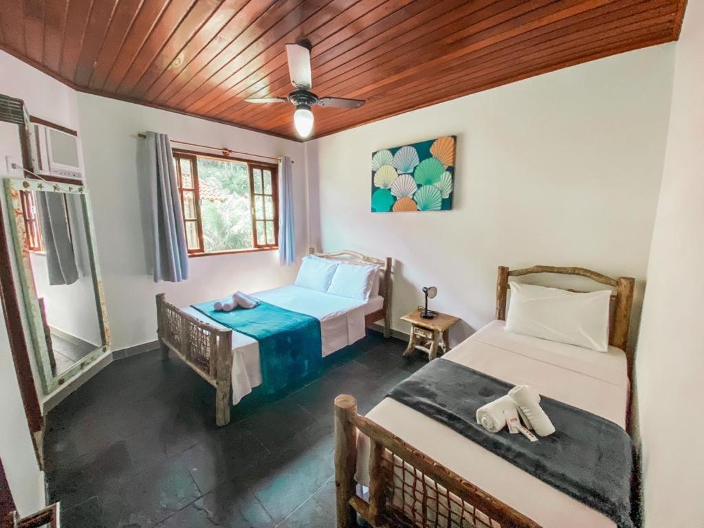 a bedroom with two beds and a ceiling fan at Pousada do Canto in Abraão