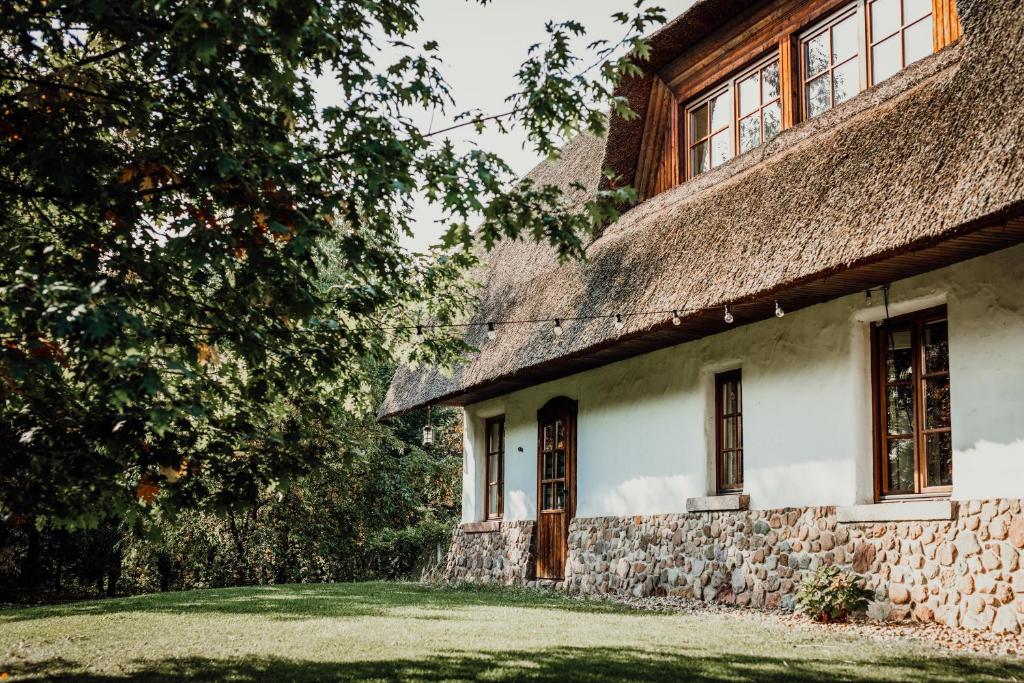 an old stone house with a thatched roof at HOT_elarnia Hotel & Spa in Puszczykowo