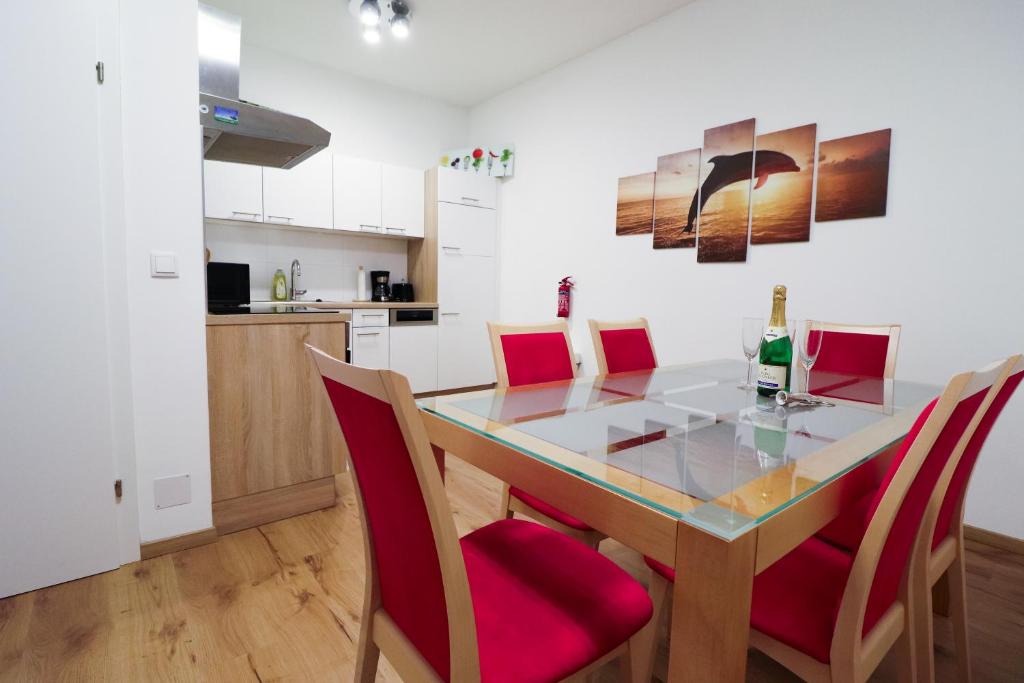 cocina y comedor con mesa de cristal y sillas rojas en CozyNite Premium Apartment Schönbrunn 1, en Viena