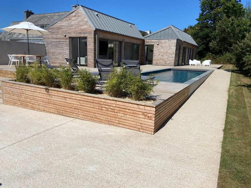 un patio trasero con una pared de ladrillo y una piscina en Magnifique villa avec piscine, à 5 min des plages en Landunvez