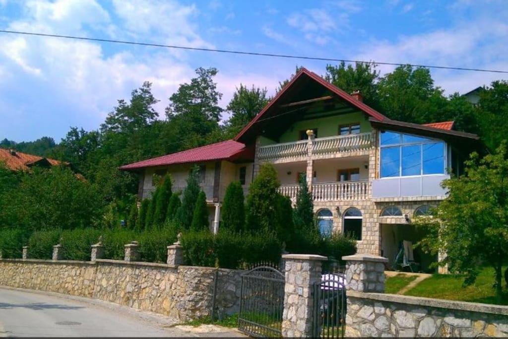 une maison avec une clôture en pierre devant elle dans l'établissement Vila Afan Ušivak, à Sarajevo