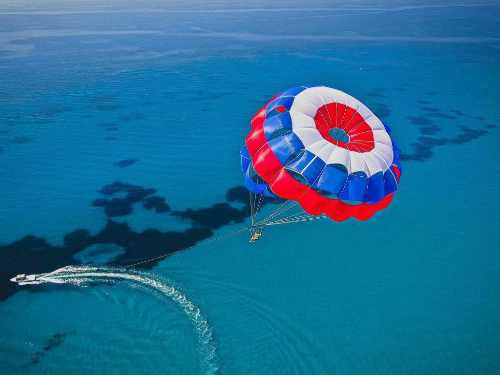 a red white and blue parachute flying over the water at PylaApts - Apartments near the beach in Pyla