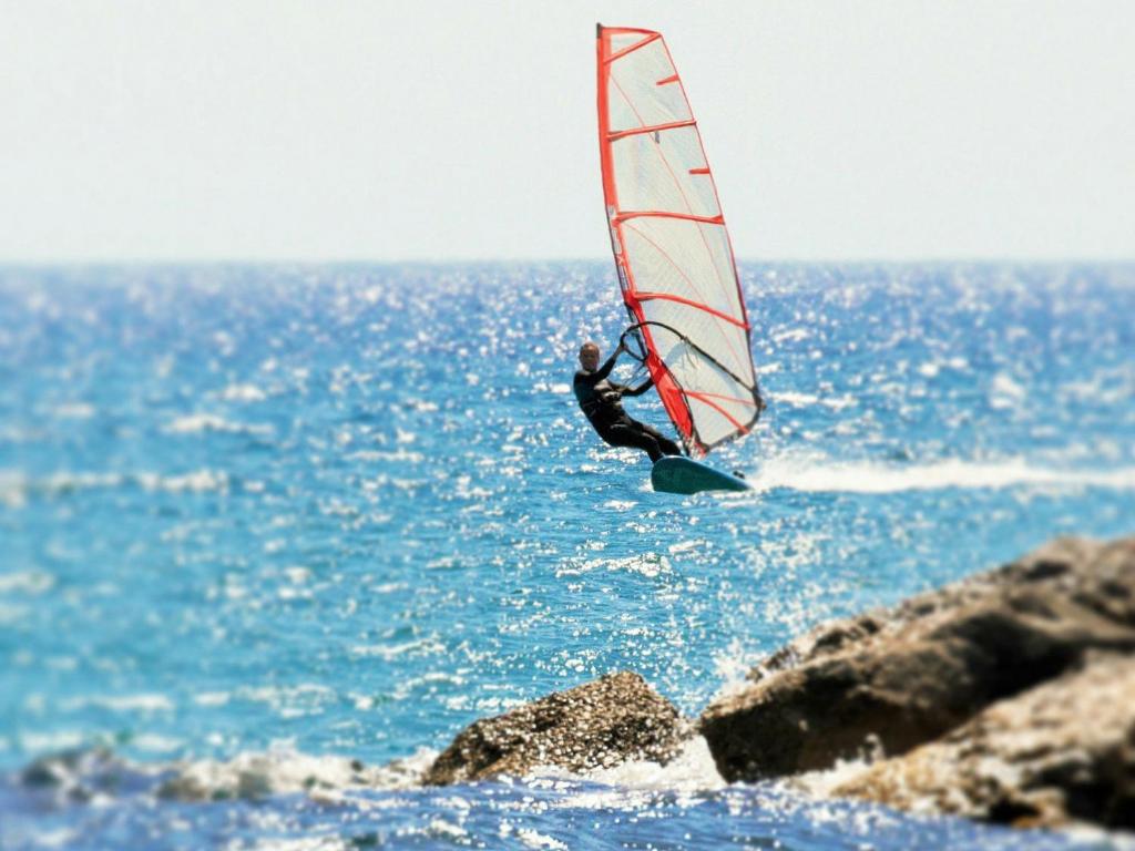 a man is windsurfing in the ocean on the water at PylaApts - Apartments near the beach in Pyla