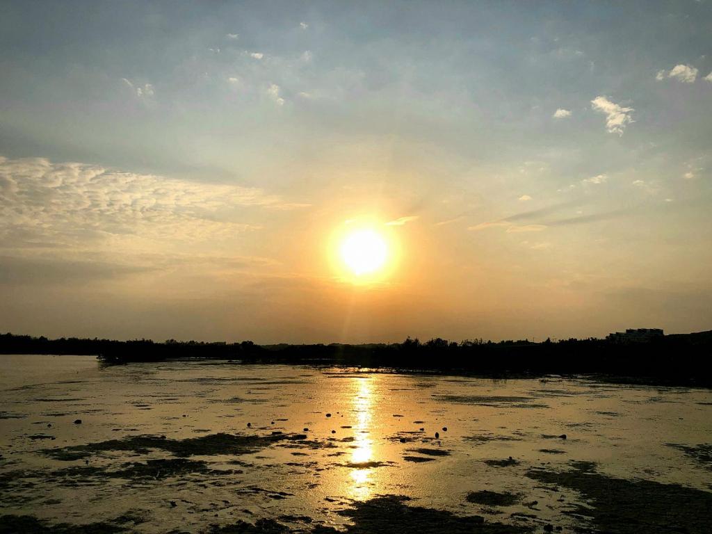 a sun setting over a body of water at PylaApts - Apartments near the beach in Pyla