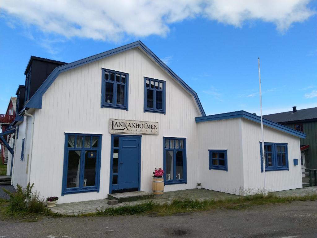 ein weißes Gebäude mit blauen Fenstern und einer blauen Tür in der Unterkunft Fredheimbrygga in Andenes