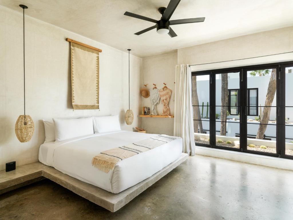 - une chambre avec un lit blanc et une grande fenêtre dans l'établissement Drift San Jose del Cabo, à San José del Cabo