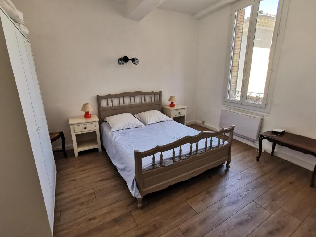 um quarto com uma cama e duas mesas e uma janela em La suite du beffroi em Malaucène