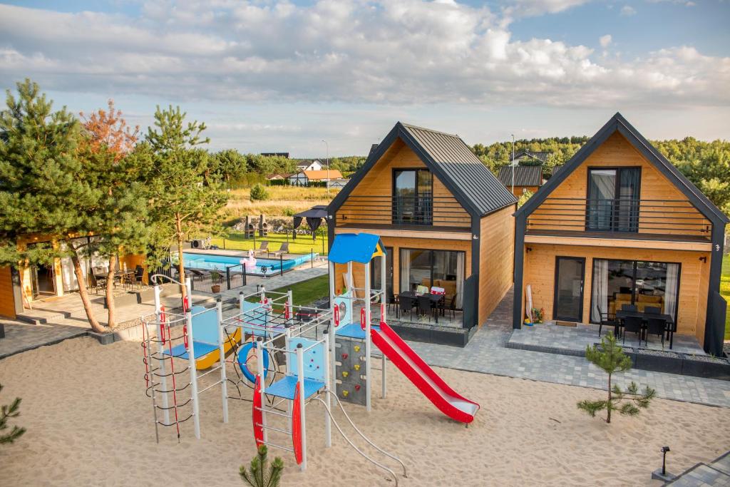 einen Spielplatz mit Rutsche vor einem Haus in der Unterkunft Huśtawka i Hamak - Domki z basenem nad morzem Ustka in Ustka