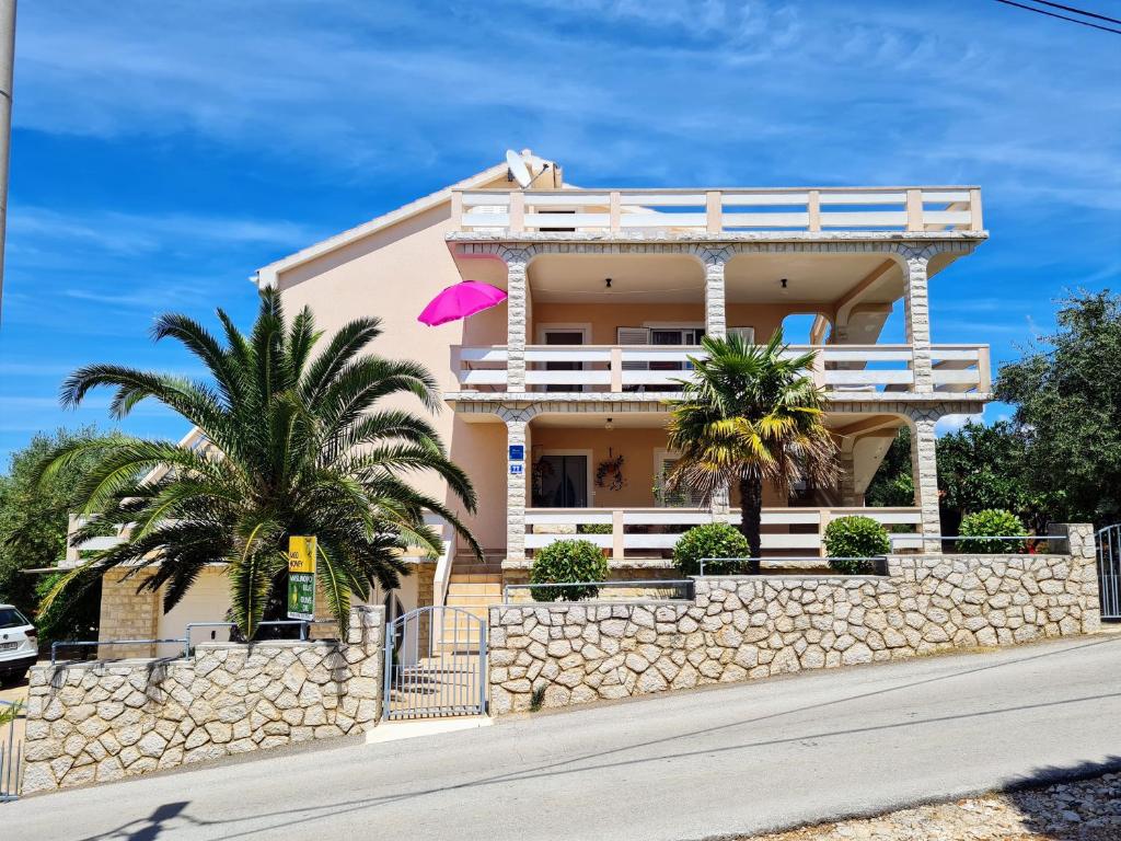 a building with palm trees and a pink umbrella at Angel in Lun