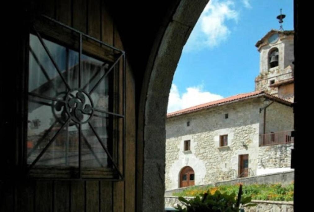 uma janela com vista para um edifício e uma torre em Hermoso Caserío Navarra. (Madoz) 