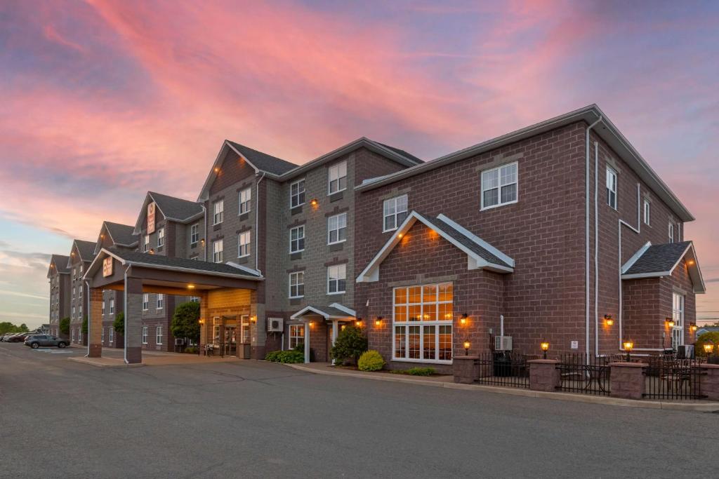 a large brick building with a sunset in the background at Best Western Plus Fredericton Hotel & Suites in Fredericton