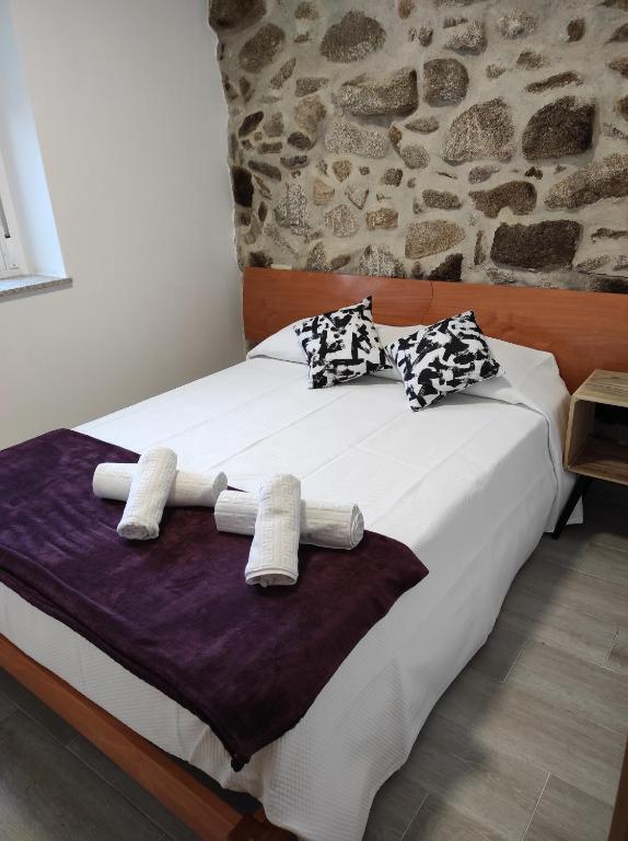 Schlafzimmer mit einem Bett mit weißer Bettwäsche und Kissen in der Unterkunft Casa do Vale - Casa Termal - Gerês / Xures in Lobios
