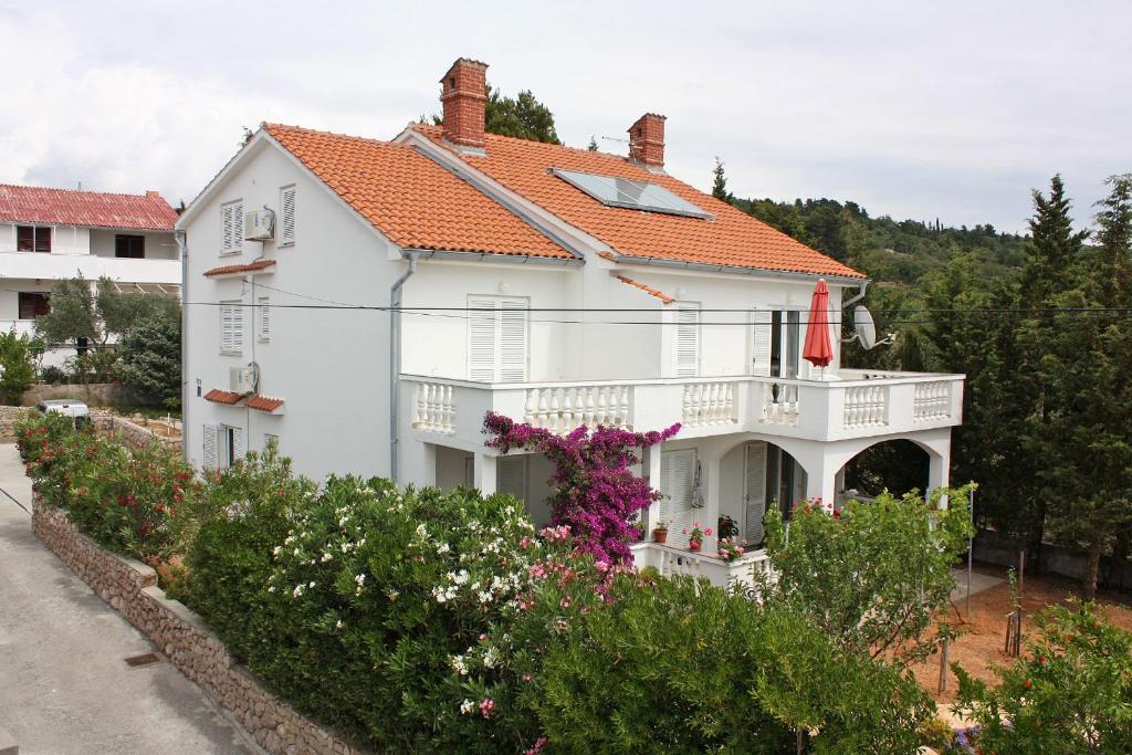 ein weißes Haus mit einem orangefarbenen Dach in der Unterkunft Apartments with parking spaces Barbat, Rab - 4962 in Rab