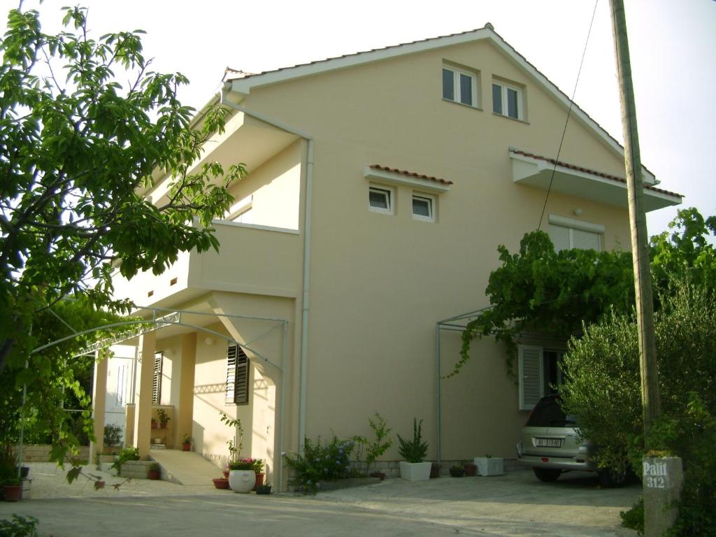 a white house with a car parked in front of it at Apartments with a parking space Palit, Rab - 4957 in Mundanije