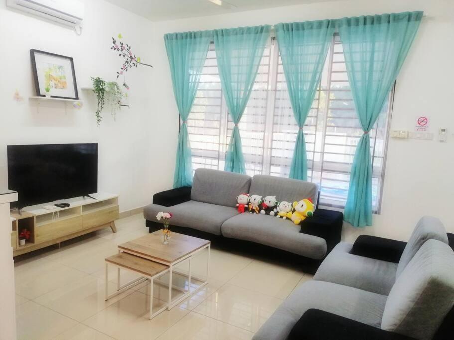 a living room with a couch and a tv at Desaru M'Cozy/12pax/Mini Pool/ Waterpark/BBQ/WIFI in Bandar Penawar
