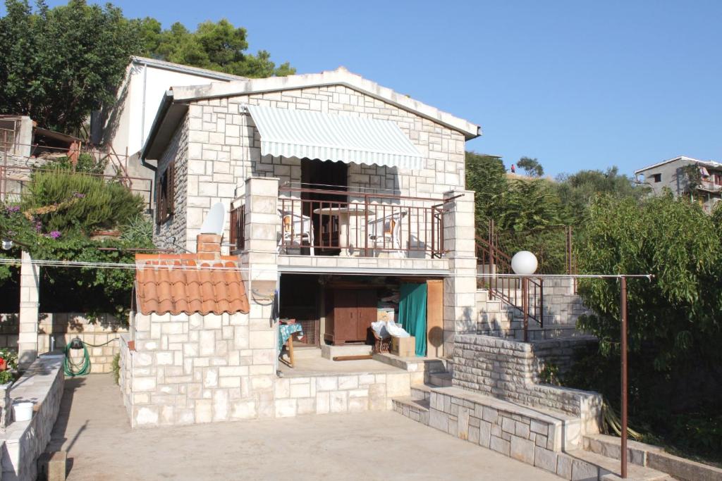 uma casa de tijolos com um alpendre e uma varanda em Apartments by the sea Stomorska, Solta - 5164 em Stomorska