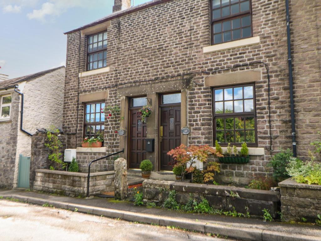 a brick house with a brown door and windows at Shenton Cottage in Buxton