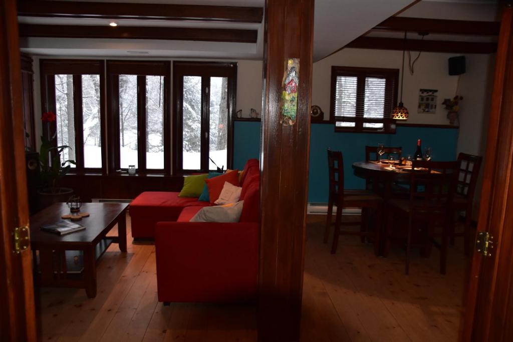 a living room with a red couch and a table at PETIT COIN DE PARADIS in Sainte Anne des Lacs