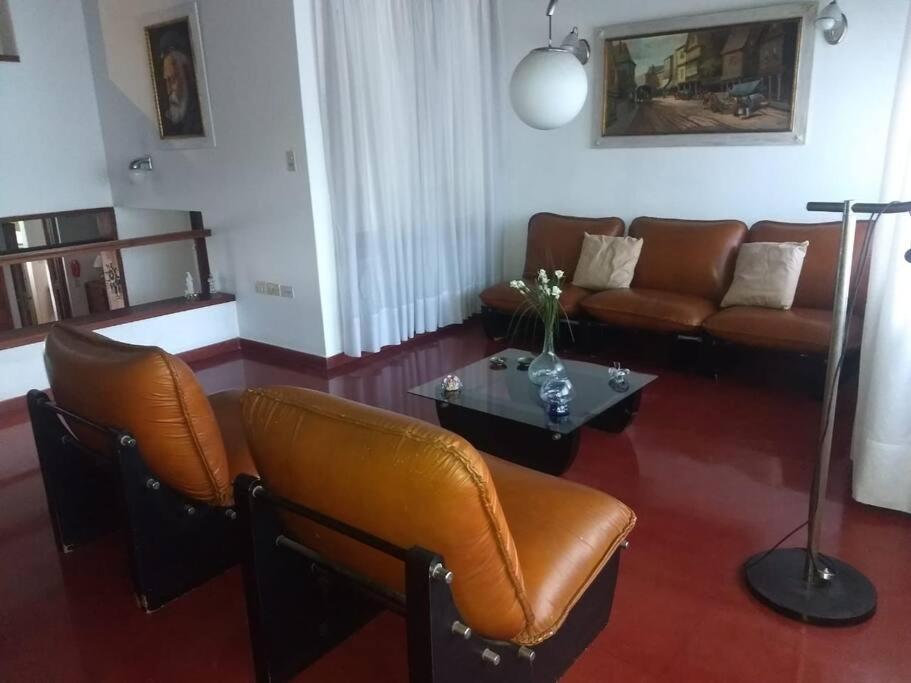 sala de estar con mesa y muebles de cuero marrón en Casa 70 en La Plata