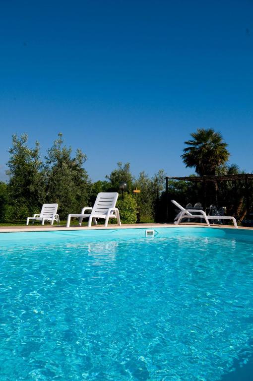 two white chairs and a swimming pool withacersacers at Agriturismo De Santis in Castiglioncello