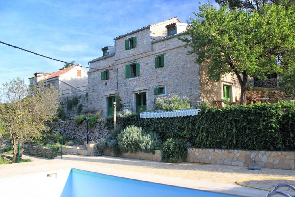 a large stone house with a swimming pool in front of it at Family friendly house with a swimming pool Talez, Vis - 8850 in Vis