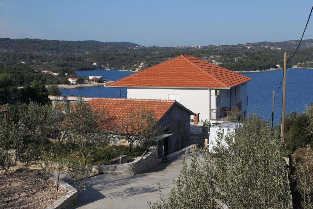 a house with an orange roof next to the water at Apartments by the sea Necujam, Solta - 8647 in Grohote