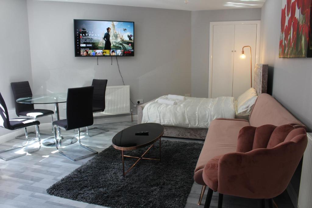 uma sala de estar com um sofá, uma mesa e uma cama em Cosy Central Luton Studio Flat -Ideal for Airport! em Luton