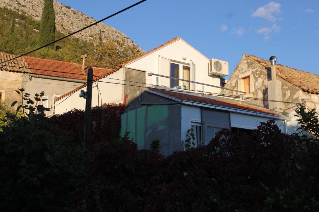 特斯特諾的住宿－Apartments with a parking space Trsteno, Dubrovnik - 8594，山上的白色房子,有绿门