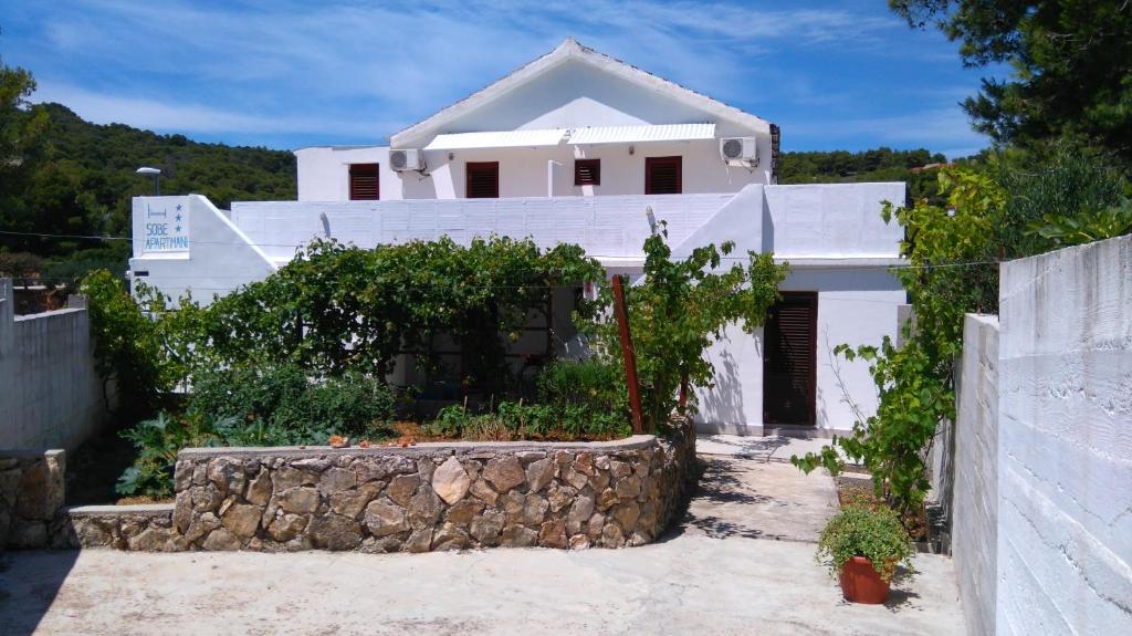 a white house with a stone wall at Studio Rukavac 8863a in Rukavac